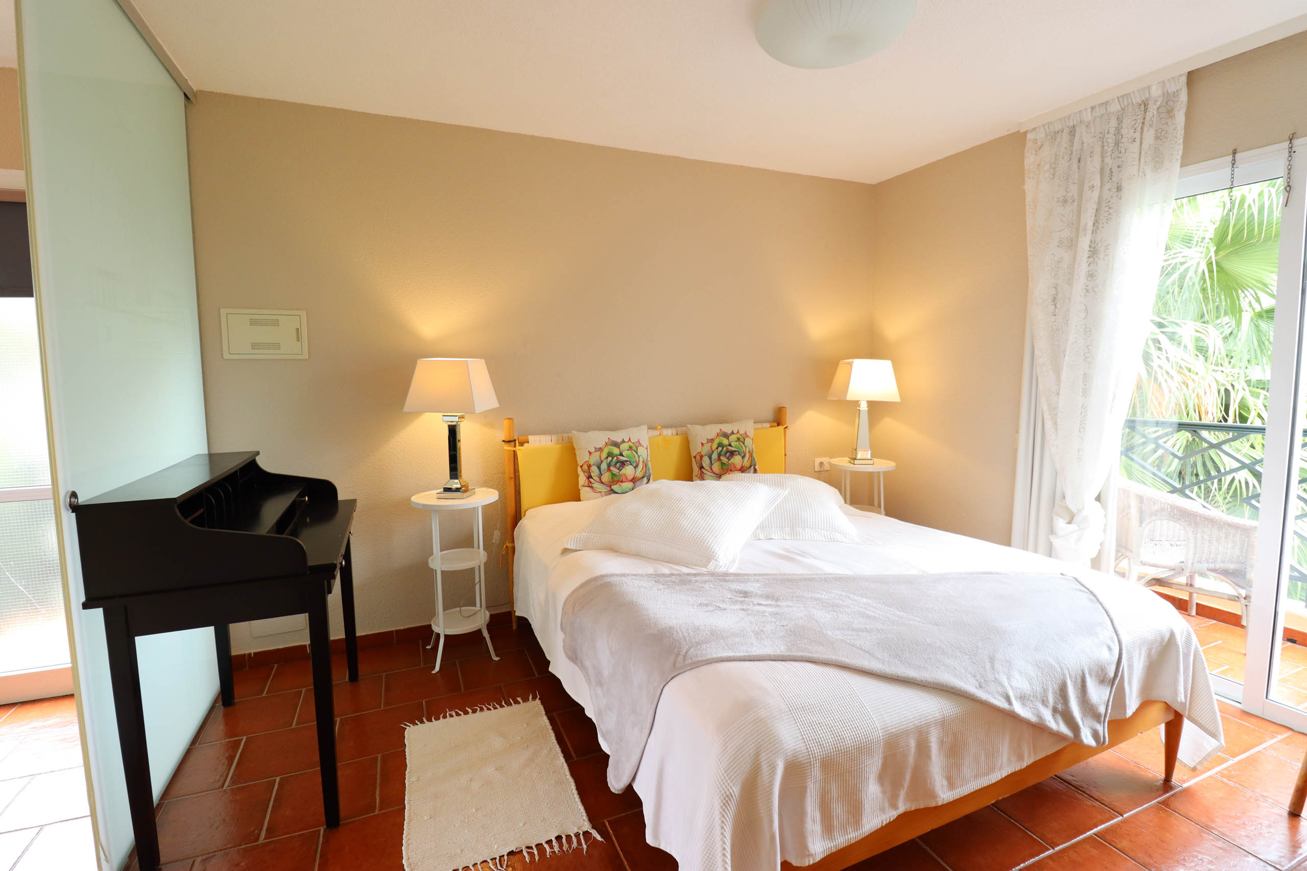 Cozy bedroom with bed, lamps, and piano